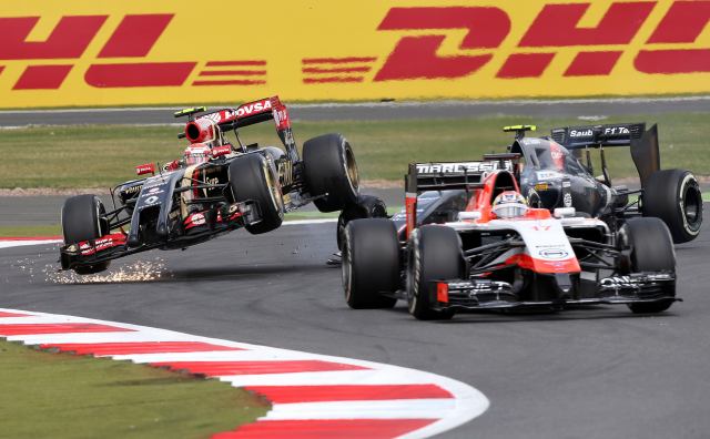 Lotus F1 team driver Pastor Maldonado of Venezuela collides with Sauber driver Esteban Gutierrez as Marussia driver Jules Bianchi of France drives on during the British Grand Prix at the Silverstone Race Circuit,