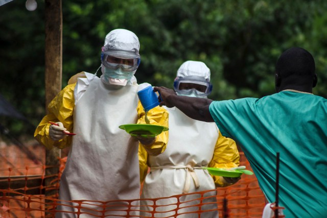 Empleados que trabajan junto a miembros de Médicos Sin Fronteras se preparan para entregar alimentos a pacientes aislados en un centro de tratamiento de ébola en Kailahun, Sierra Leona