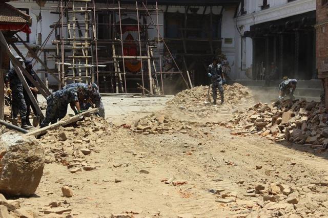 Fotografía tomada el día 24 de mayo en la que miembros de las Fuerzas de Seguridad nepalíes retiran escombros en la zona de Durbar de Katmandú donde se encuentran monumentos declarados Patrimonio de la Humanidad de la Unesco, gravemente dañados por el terremoto del 25 de abril que asoló Nepal. Pieza a pieza Nepal busca entre sus escombros el patrimonio que el terremoto trató de arrebatarle, y en algunos casos los vecinos salvaron, con el propósito de prepararse para la llegada del monzón y adelantar un trabajo de restauración que deberá esperar a que pase el verano. Un mes después de un seísmo que tumbó como naipes templos, palacios y edificios históricos, la Unesco trabaja contra el reloj y con la preocupación oteando el horizonte ante la inminente llegada de las lluvias del monzón a partir de junio. EFE/Luis Ángel Reglero