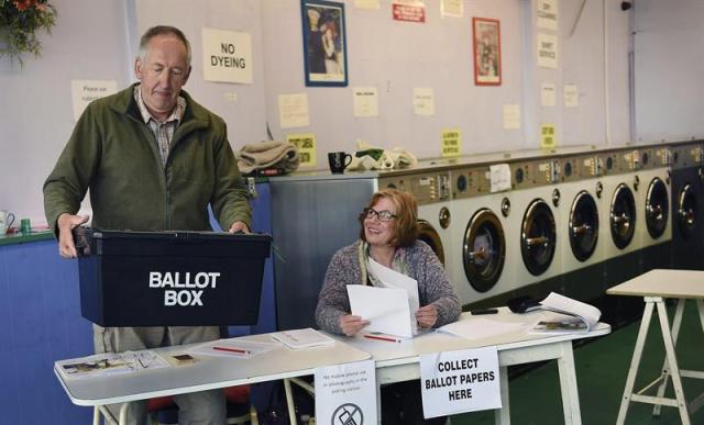 Los encargados de la mesa preparan las urnas en una lavandería establecida como colegio electoral en Oxford (Reino Unido) hoy, jueves 7 de mayo de 2015. Según las encuestas, las dos formaciones mayoritarias están igualadas en intención de voto, ambas con cerca del 34 % de apoyo, y no obtendrían una mayoría suficiente para gobernar en solitario. EFE/Andy Rain