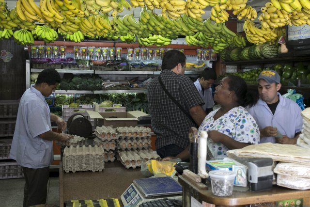 A customer selects bananas as others buy goods at a fruit and vegetable store in Caracas, July 10, 2015. A debilitating recession and a drop in oil prices have harmed the OPEC nation's ability to provide dollars through its complex three-tiered currency control system, pushing up the black market rate at a dizzying speed. The bolivar sank past 600 per U.S. dollar on Thursday, compared with 73 a year ago, according to anti-government website DolarToday.REUTERS/Marco Bello
