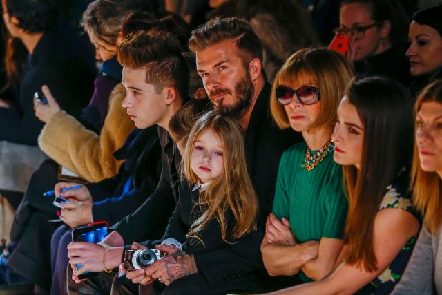 British former soccer player David Beckham sits next to U.S. Vogue editor Anna Wintour (3rd R) with his daughter, Harper, on his lap during a presentation of the Victoria Beckham Fall/Winter 2015 collection during New York Fashion Week