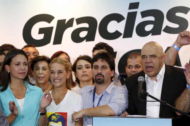 Jesus Torrealba (R), secretary of the Venezuelan coalition of opposition parties (MUD), speaks near Lilian Tintori (2nd L), wife of jailed Venezuelan opposition leader Leopoldo Lopez during a news conference in Caracas December 7, 2015. Venezuela's opposition won control of the legislature from the ruling Socialists for the first time in 16 years on Sunday, giving them a long-sought platform to challenge President Nicolas Maduro. The banner reads, "Thanks". REUTERS/Carlos Garcia Rawlins