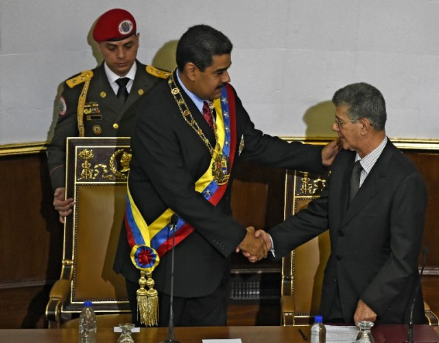 Venezuelan President Nicolas Maduro (C) shakes hands with the president of the opposition controlled National Assembly, Henry Ramos Allup (R), during his annual report at the National Assembly in Caracas on January 15, 2016. Venezuela's President Nicolas Maduro decreed a two-month state of "economic emergency" Friday, seizing the initiative ahead of a key showdown in his standoff with the opposition in the oil-rich nation. Venezuela's economy contracted 4.5 percent in the first nine months of 2015, the central bank said Friday, the first official data in more than a year on the magnitude of the South American oil giant's recession. AFP PHOTO / JUAN BARRETO / AFP / JUAN BARRETO