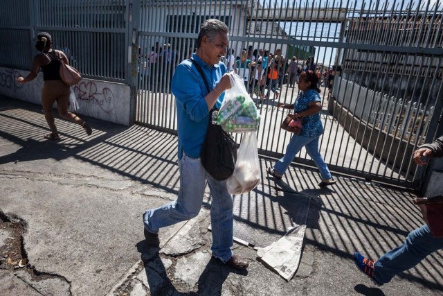 CAR01. CARACAS (VENEZUELA), 16/01/2016.- Un hombre corre luego de comprar arroz en un abasto hoy, sábado 16 de enero de 2016, en la ciudad de Caracas (Venezuela). Venezuela, con las mayores reservas probadas de petróleo del mundo, se declaró en emergencia económica para atender la situación del país que después de un año de opacidad reveló una inflación interanual de 141,5 por ciento -la más alta de toda su historia-, y una contracción del 4,5 por ciento. EFE/MIGUEL GUTIÉRREZ