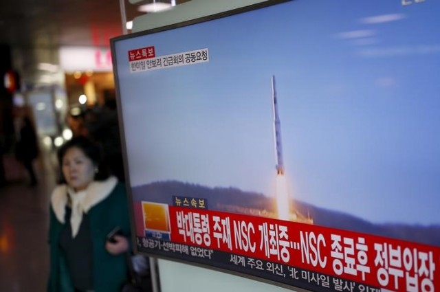 Una persona camina junto a una pantalla de televisor que muestra una noticia sobre el lanzamiento de un cohete de largo alcance por parte de Corea del Norte, Reuters/Archivo