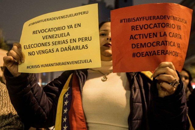 Venezuelan citizens in Peru hold signs during a protest against the visit of the president of the Venezuelan National Electoral Board (TSJ), Tibisay Lucena (not in frame), in Lima on June 01, 2016.  / AFP PHOTO / ERNESTO BENAVIDES