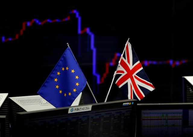 Una bandera británica y una bandera de la UE se ven frente a un monitor que muestra un gráfico de la tasa de cambio del yen japonés frente al dólar de EE.UU. en una empresa de comercio de divisas en Tokio, Japón, 27 de junio de 2016. REUTERS / Toru Hanai
