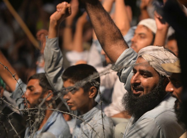 Los hombres levantan sus puños cerca de alambre de púas en una manifestación para mostrar su solidaridad con los musulmanes de Cachemira de la India a medida que observan un "Día Negro" para denunciar las acciones de las fuerzas de seguridad indias en Cachemira administrada por la India, en Islamabad el 20 de julio de 2016. Los disturbios en Cachemira ha provocado la muerte de 45 civiles y herido a 3.600 en enfrentamientos entre las fuerzas del gobierno indio de Cachemira de la India y los manifestantes provocadas por el asesinato de un joven rebelde carismático, con un estricto toque de queda en su lugar por un día 12. AAMIR QURESHI / AFP 
