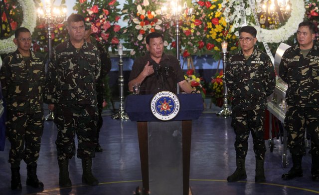 Philippine President Rodrigo Duterte speaks in between military officials, at the wake of a soldier killed in an encounter with communist rebels at a military Camp Panacan in Davao city, in southern Philippines August 7, 2016. REUTERS/Lean Daval Jr