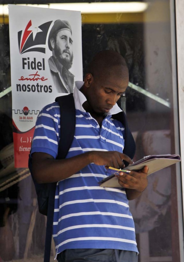 HAB101. LA HABANA (CUBA), 09/08/2016.- Un hombre revisa sus anotaciones hoy, martes 09 de agosto del 2016, en La Habana (Cuba), junto a un cartel alusivo al cumpleaños 90 del líder de la revolución cubana Fidel Castro este próximo sábado 13 de agosto. EFE/Ernesto Mastrascusa