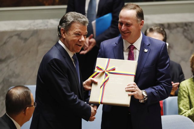 Colombia's President Juan Manuel Santos Calderon (L) presents the Prime Minister of New Zealand John Key with the peace agreement between Colombia and the FARC during a meeting of the United Nations Security Council during the 71st session of the U.N. General Assembly at U.N. headquarters in New York, U.S., September 21, 2016. REUTERS/Lucas Jackson