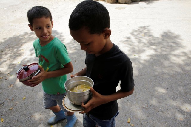 Los chicos reciben comida gratis que fue preparada por residentes y voluntarios en una calle del barrio de bajos ingresos de Caucaguita en Caracas, Venezuela 17 de septiembre de 2016. REUTERS / Henry Romero
