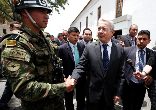 Colombian former President and Senator Alvaro Uribe shakes hands with a soldier before a meeting with Colombia's President Juan Manuel Santos at Narino Palace in Bogota, Colombia