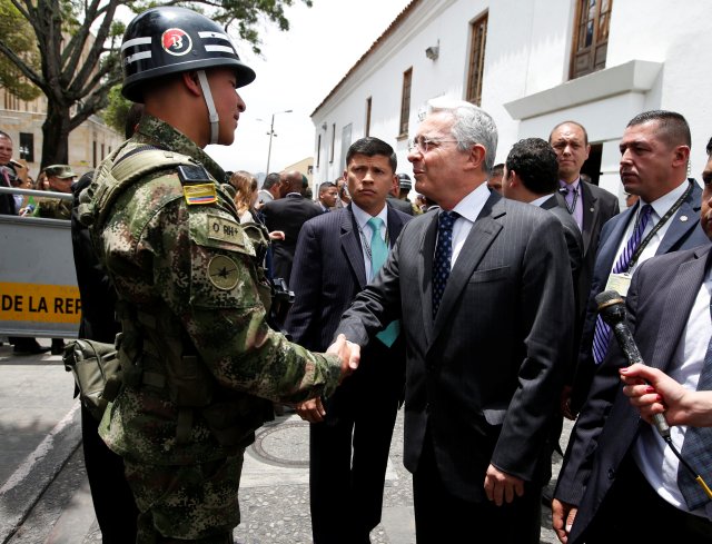 Colombian former President and Senator Uribe shakes hands with a soldier before a meeting with Colombia's President Santos at Narino Palace in Bogota, Colombia