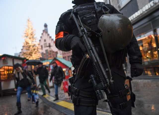 A policeman with machine gun stands guard at the Christmas market at the Roemerberg in the centre of Frankfurt am Main, western Germany, on December 22, 2016, as security measures are taken after the deadly Christmas market attack in Berlin. As police hunt for Tunisian Anis Amri, the top suspect in Berlin's Christmas market attack, public anger has grown over a catalogue of failures that allowed him to evade arrest or deportation. / AFP PHOTO / dpa / Arne Dedert / Germany OUT