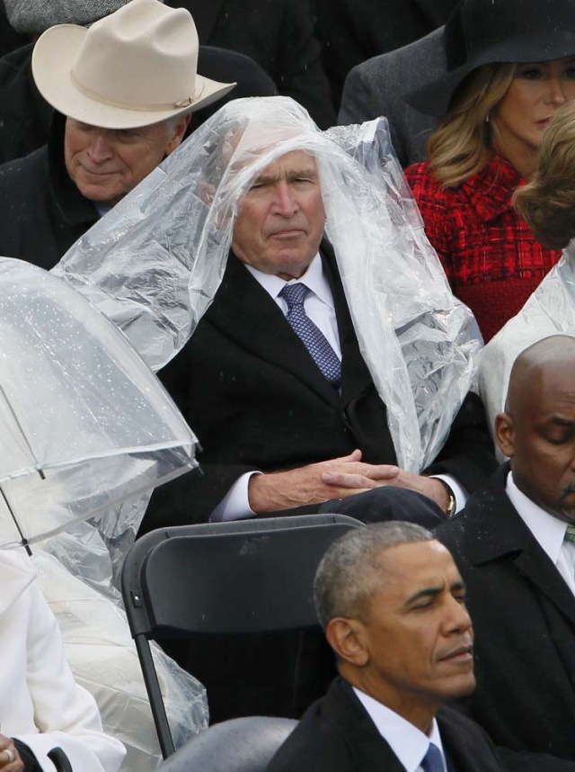Former President George W. Bush keeps covered under the rain during the inauguration ceremonies swearing in Donald Trump as the 45th president of the United States on the West front of the U.S. Capitol in Washington, U.S., January 20, 2017. REUTERS/Rick Wilking