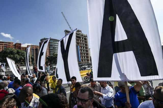 Opponents of Venezuelan President Nicolas Maduro protest at the main highway of Caracas on January 24, 2017. Venezuelan opponents protested to demand early elections, with the aim of ousting President Nicolas Maduro, who they blame for the profound political and economic crisis that has the country in its grip. / AFP PHOTO / JUAN BARRETO