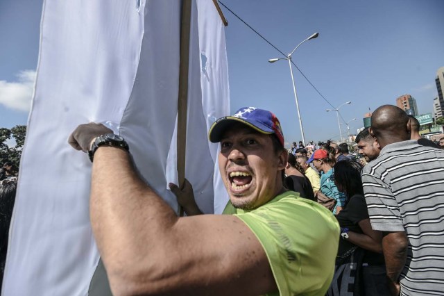 Opponents of Venezuelan President Nicolas Maduro protest at the main highway of Caracas on January 24, 2017. Venezuelan opponents protested to demand early elections, with the aim of ousting President Nicolas Maduro, who they blame for the profound political and economic crisis that has the country in its grip. / AFP PHOTO / JUAN BARRETO