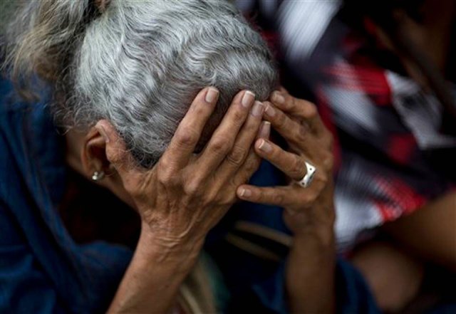 Una mujer se sujeta la cabeza con las manos mientras espera en una fila en el exterior de un supermercado para comprar comida, en Caracas, Venezuela (Foto Ariana Cubillos/AP)