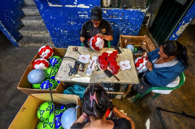 Workers make footballs at a ball factory in Mongui, in the Colombian department of Boyaca, on February 13, 2017. Mongui, in the central mountains of Colombia, has about 20 football factories that make balls mainly for football and micro-football. About a quarter of the town's 4,900 inhabitants work in these factories. / AFP PHOTO / Luis ACOSTA