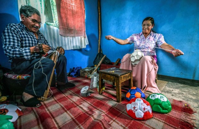 Workers Jose Sierra (L) and Vitalina Mesa sew footballs by hand at a ball factory in Mongui, in the Colombian department of Boyaca, on February 13, 2017. Mongui, in the central mountains of Colombia, has about 20 football factories that make balls mainly for football and micro-football. About a quarter of the town's 4,900 inhabitants work in these factories. / AFP PHOTO / Luis ACOSTA