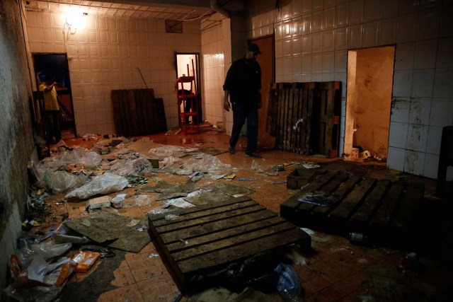 Workers look for valuables among the damaged goods in a supermarket, after it was looted in Caracas, Venezuela April 21, 2017. REUTERS/Carlos Garcia Rawlins