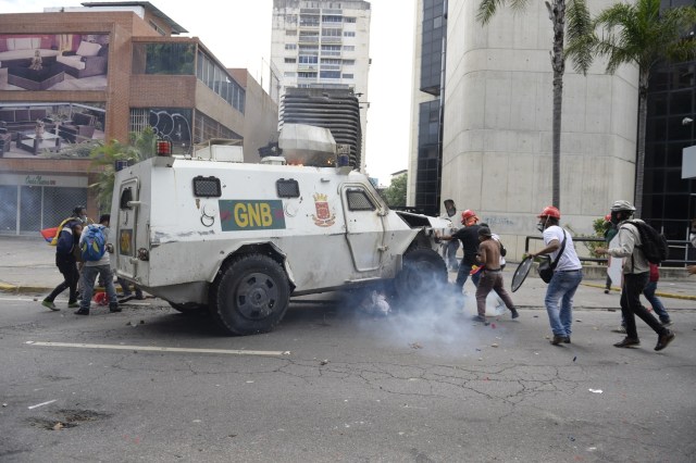 A Venezuelan National Guard riot control vehicle runs over an opposition demonstrator during a protest against Venezuelan President Nicolas Maduro, in Caracas on May 3, 2017. Venezuela's angry opposition rallied Wednesday vowing huge street protests against President Nicolas Maduro's plan to rewrite the constitution and accusing him of dodging elections to cling to power despite deadly unrest. / AFP PHOTO / FEDERICO PARRA / GRAPHIC CONTENT