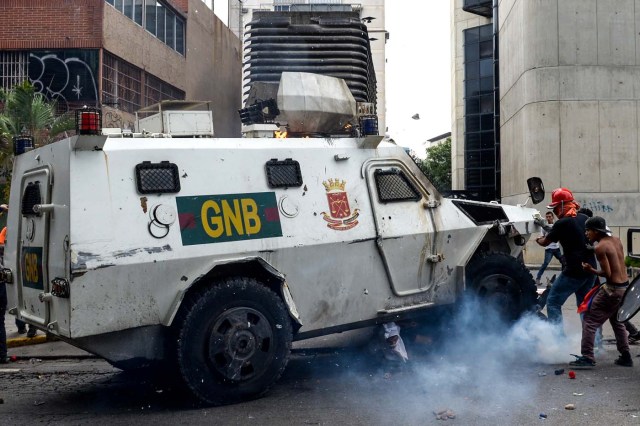 A Venezuelan National Guard riot control vehicle runs over an opposition demonstrator during a protest against Venezuelan President Nicolas Maduro, in Caracas on May 3, 2017. Venezuela's angry opposition rallied Wednesday vowing huge street protests against President Nicolas Maduro's plan to rewrite the constitution and accusing him of dodging elections to cling to power despite deadly unrest. / AFP PHOTO / FEDERICO PARRA