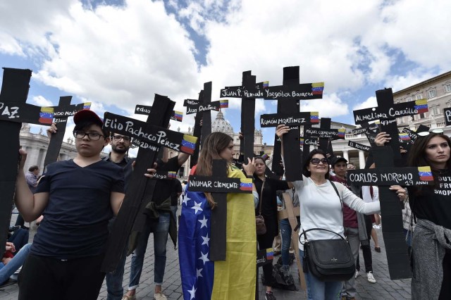 Members of the Venezuelian community hold black crosses with names of victims of clashes with police during protests against Venezuela's President Nicolas Maduro, on May 7, 2017  at St Peter's square before the Regina Coeli prayer of Pope Francis in Vatican. Pope Francis last week made a heartfelt appeal for "negotiated solutions" to end the violence in crisis-torn Venezuela for the sake of an "exhausted population".  The death toll since April -- when the protests intensified after Maduro's administration and the courts stepped up efforts to undermine the opposition -- is at least 36, according to prosecutors, with hundreds more injured. / AFP PHOTO / TIZIANA FABI