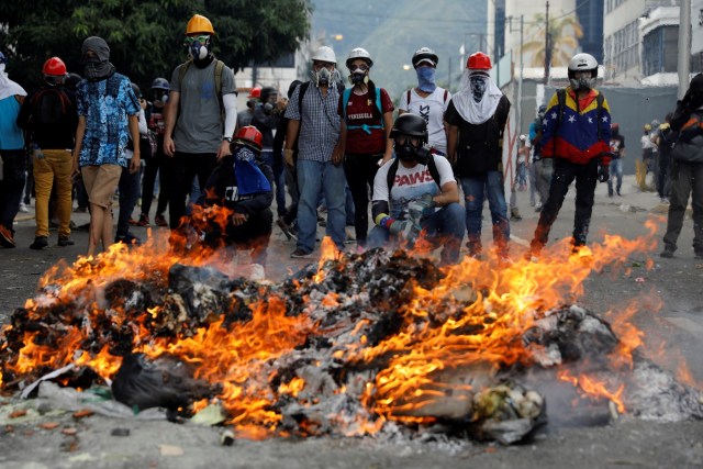 Opposition supporters stand in front of a fire during clashes with riot police at a rally against President Nicolas Maduro in Caracas, Venezuela May 3, 2017. REUTERS/Carlos Garcia Rawlins
