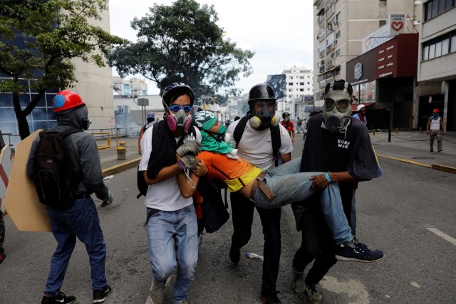 An injured opposition supporter is helped by others during a rally against President Nicolas Maduro in Caracas, Venezuela, May 3, 2017. REUTERS/Carlos Garcia Rawlins