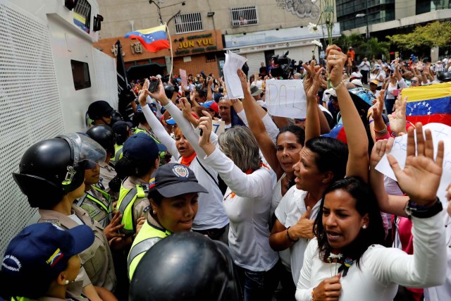 Women lift their hands in front of the police during a women's march to protest against President Nicolas Maduro's government in Caracas, Venezuela May 6, 2017. REUTERS/Carlos Garcia Rawlins