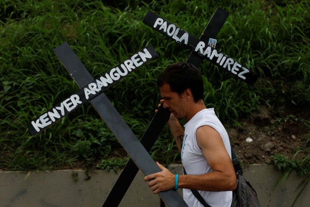 An opposition supporter carries crosses with the names of victims of violence during the protests against Venezuela's President Nicolas Maduro's government, during a protest in Caracas, Venezuela May 15, 2017. REUTERS/Carlos Garcia Rawlins