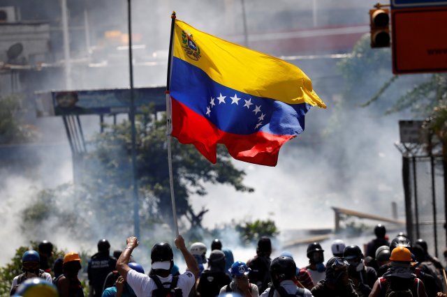 A demonstrator waves a Venezuelan flag during riots at a march to state Ombudsman's office in Caracas, Venezuela May 29, 2017. REUTERS/Carlos Garcia Rawlins