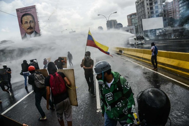Opposition demonstrators clash with riot police in Caracas, on May 31, 2017. Venezuelan authorities on Wednesday began signing up candidates for a planned constitutional reform body, a move that has inflamed deadly unrest stemming from anti-government protests. / AFP PHOTO / FEDERICO PARRA