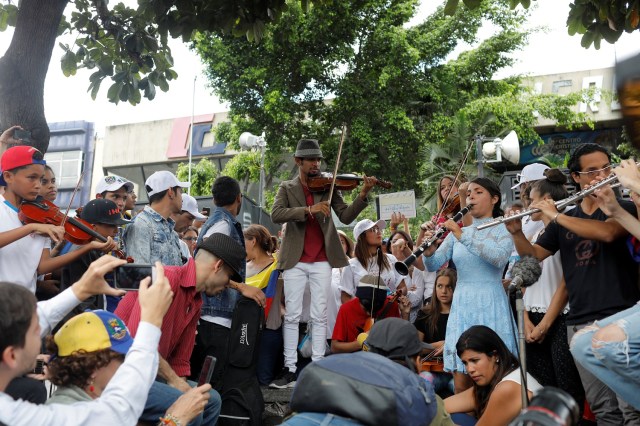 Venezuelan violinist Wuilly Arteaga (C) plays music next to other young musicians during a gathering against Venezuela's President Nicolas Maduro's government in Caracas, Venezuela June 4, 2017. REUTERS/Marco Bello