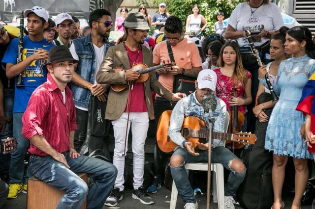 El violinista Wuilly Arteaga (c), un músico que ganó popularidad en el país luego de que su instrumento terminara dañado en medio de una protesta opositora que se tornó violenta, se presenta junto a otros músicos frente a un centenar de personas hoy, domingo 4 de junio de 2017, en la Plaza Brión de Chacaíto, en Caracas (Venezuela). Decenas de venezolanos se manifestaron en Caracas a favor de la paz y en contra del Gobierno de Nicolás Maduro, mientras la coalición opositora Mesa de la Unidad Democrática (MUD) llamó a sus simpatizantes a participar mañana en un "plantón" en varias vías del país. EFE/MIGUEL GUTIÉRREZ