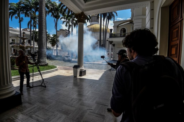 Journalists react as supporters of Venezuelan President Nicolas Maduro storm into the National Assembly building in Caracas on July 5, 2017 as opposition deputies hold a special session on Independence Day. A political and economic crisis in the oil-producing country has spawned often violent demonstrations by protesters demanding President Nicolas Maduro's resignation and new elections. The unrest has left 91 people dead since April 1. / AFP PHOTO / Juan BARRETO