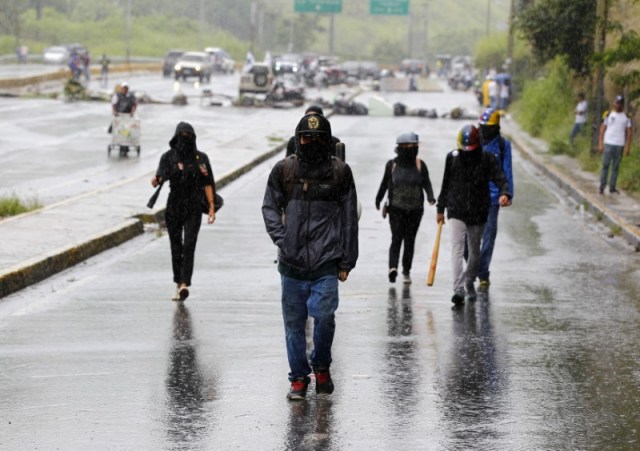 Manifestantes caminan bajo la lluvia en Caracas, donde se produjeron fuertes enfrentamientos en el día de una polémica elección de Asamblea Constituyente.  Julio 30, 2017. REUTERS/Christian Veron