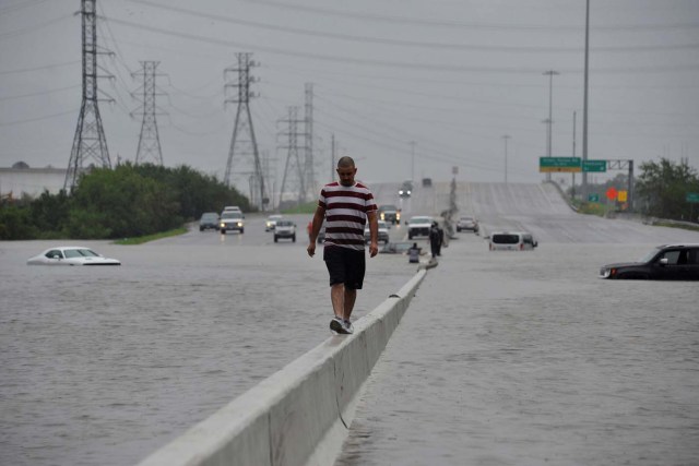 A stranded motorist escapes floodwaters on Interstate 225 after Hurricane Harvey inundated the Texas Gulf coast with rain causing mass flooding, in Houston, Texas, U.S. August 27, 2017. REUTERS/Nick Oxford