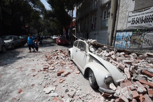 Picture of a car crashed by debris from a damaged building after a quake rattled Mexico City on September 19, 2017. A powerful earthquake shook Mexico City on Tuesday, causing panic among the megalopolis' 20 million inhabitants on the 32nd anniversary of a devastating 1985 quake. The US Geological Survey put the quake's magnitude at 7.1 while Mexico's Seismological Institute said it measured 6.8 on its scale. The institute said the quake's epicenter was seven kilometers west of Chiautla de Tapia, in the neighboring state of Puebla. / AFP PHOTO / Alfredo ESTRELLA