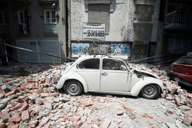 Picture of a car crashed by debris from a damaged building after a quake rattled Mexico City on September 19, 2017. A powerful earthquake shook Mexico City on Tuesday, causing panic among the megalopolis' 20 million inhabitants on the 32nd anniversary of a devastating 1985 quake. The US Geological Survey put the quake's magnitude at 7.1 while Mexico's Seismological Institute said it measured 6.8 on its scale. The institute said the quake's epicenter was seven kilometers west of Chiautla de Tapia, in the neighboring state of Puebla. / AFP PHOTO / Alfredo ESTRELLA