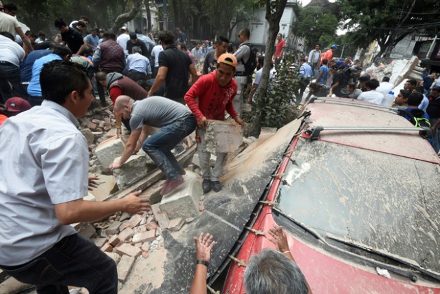 People remove debris of a building which collapsed after a quake rattled Mexico City on September 19, 2017. A powerful earthquake shook Mexico City on Tuesday, causing panic among the megalopolis' 20 million inhabitants on the 32nd anniversary of a devastating 1985 quake. The US Geological Survey put the quake's magnitude at 7.1 while Mexico's Seismological Institute said it measured 6.8 on its scale. The institute said the quake's epicenter was seven kilometers west of Chiautla de Tapia, in the neighboring state of Puebla. / AFP PHOTO / Alfredo ESTRELLA