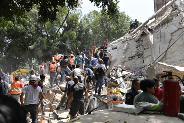 People remove debris of a collapsed building looking for possible victims after a quake rattled Mexico City on September 19, 2017. A powerful earthquake shook Mexico City on Tuesday, causing panic among the megalopolis' 20 million inhabitants on the 32nd anniversary of a devastating 1985 quake. The US Geological Survey put the quake's magnitude at 7.1 while Mexico's Seismological Institute said it measured 6.8 on its scale. The institute said the quake's epicenter was seven kilometers west of Chiautla de Tapia, in the neighboring state of Puebla. / AFP PHOTO / Omar TORRES