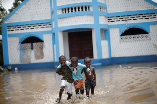 Boys gesture to the camera as they walk in a flooded area after hurricane Irma in Fort Liberte, Haiti September 8, 2017. REUTERS/Andres Martinez Casares