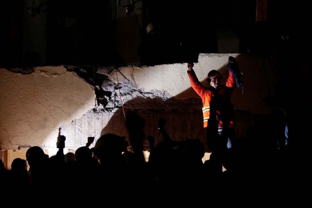 Rescue workers make a silent gesture as they search through rubble during a floodlit search for students at Enrique Rebsamen school in Mexico City, Mexico September 19, 2017. Picture taken September 19, 2017. REUTERS/Carlos Jasso