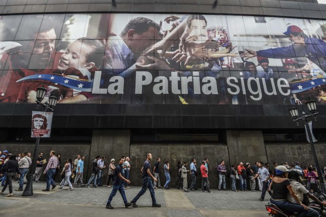 People queue to withdraw money from an ATM in Caracas on November 14, 2017. Venezuela has been declared in "selective default" by Standard and Poor's after failing to make interest payments on bond issues as it tries to refinance its $150 billion foreign debt. / AFP PHOTO / Juan BARRETO