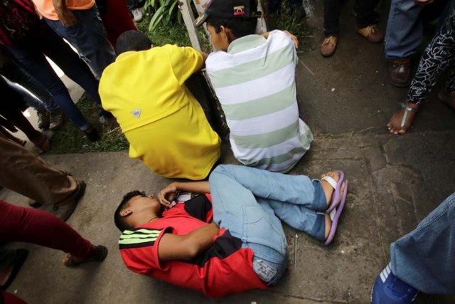 Un joven se encuentra en el piso afuera de un centro de salud mientras espera recibir tratamiento para la malaria, en San Félix, Venezuela, el 3 de noviembre de 2017. Foto tomada el 3 de noviembre de 2017. REUTERS / William Urdaneta