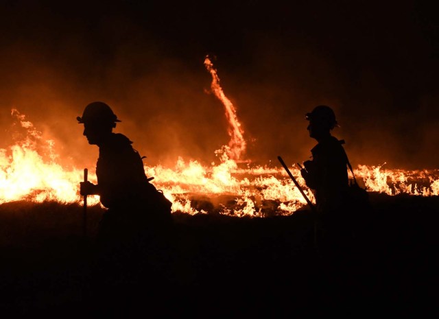 Firefighters light backfires as they try to contain the Thomas wildfire which continues to burn in Ojai, California, on December 9, 2017. Brutal winds that fueled southern California's firestorm finally began to ease Saturday, giving residents and firefighters hope for respite as the destructive toll of multiple blazes came into focus. / AFP PHOTO / MARK RALSTON